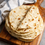 20 Mins Gluten Free Flour Tortillas -Only 5 Ingredients! 4 Soft gluten free flour tortillas stacked on a board